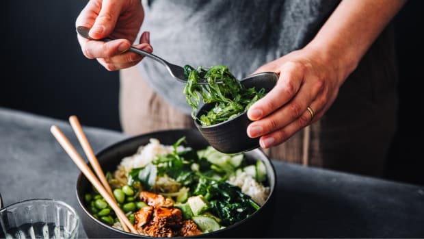 Man dishing greens onto a protein salad. Best Fat Burning Foods